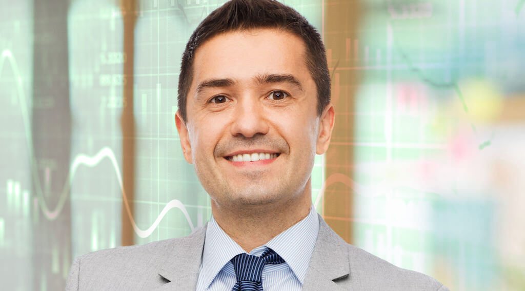 Businessman in front of a wall of financial trading charts